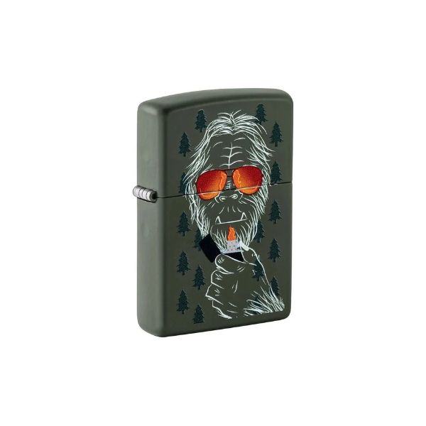 A matte dark olive green Zippo-style lighter featuring a graphic illustration of a Yeti wearing orange-tinted sunglasses and holding a cigarette, surrounded by small pine trees, shown on a plain white background.