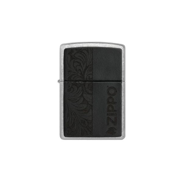 A Zippo lighter with a brushed silver metal body and a black textured cover featuring an embossed floral pattern on the left and the brand name &
