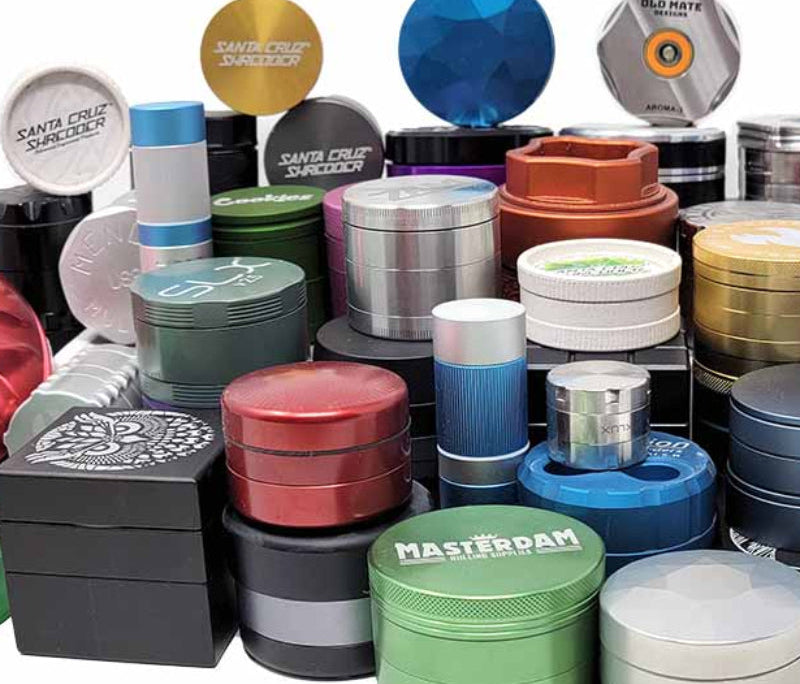 Collection of colorful metal grinder containers on a white background